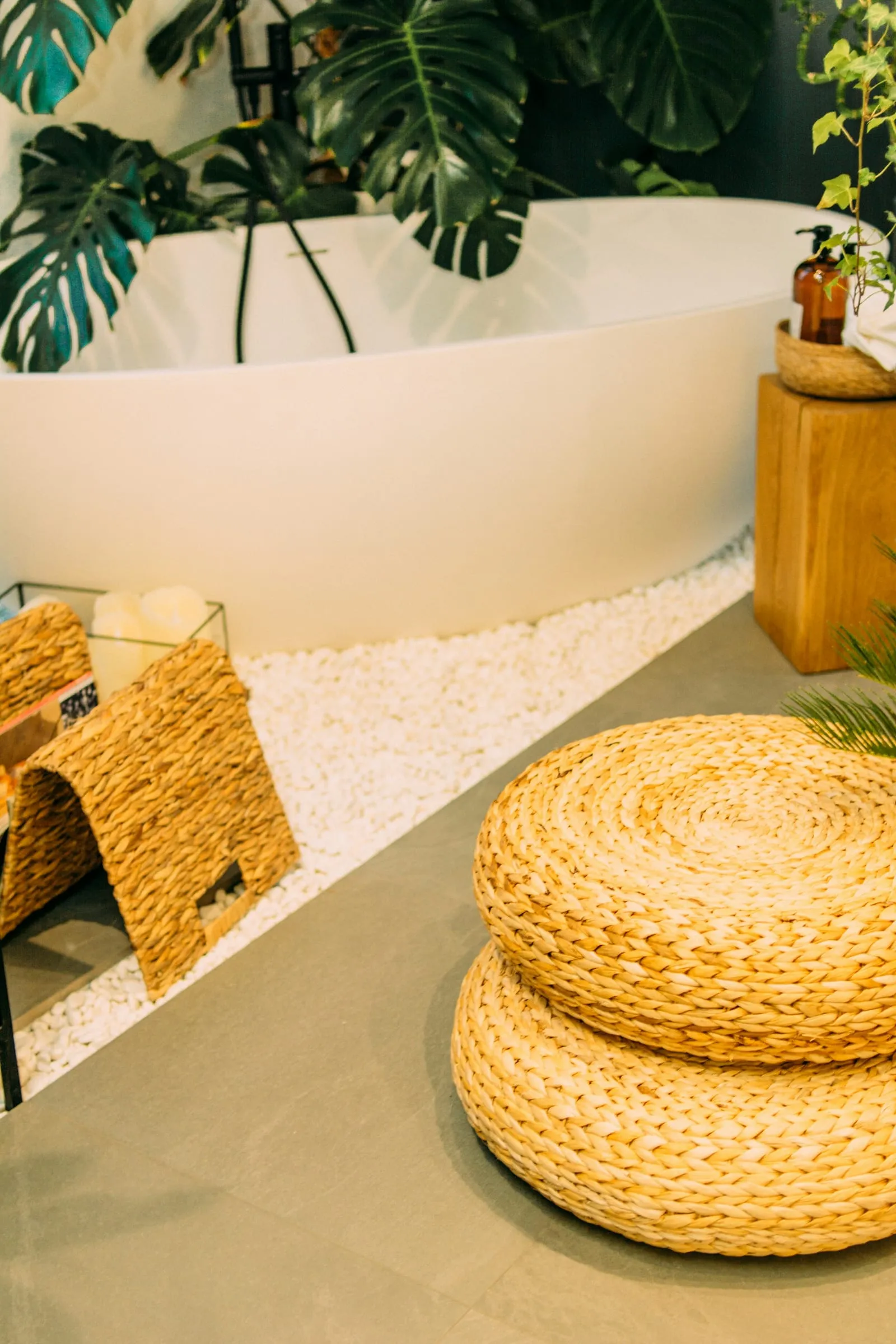 A calm treatment room with a freestanding tub, woven seating and large tropical foliage.